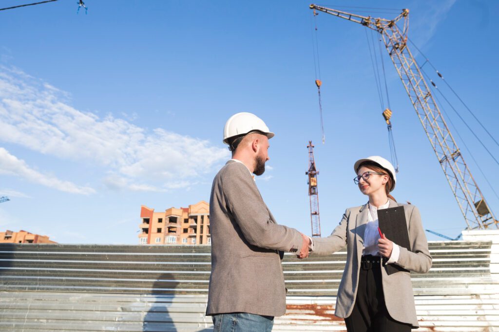 two professional engineer shaking hand construction site
